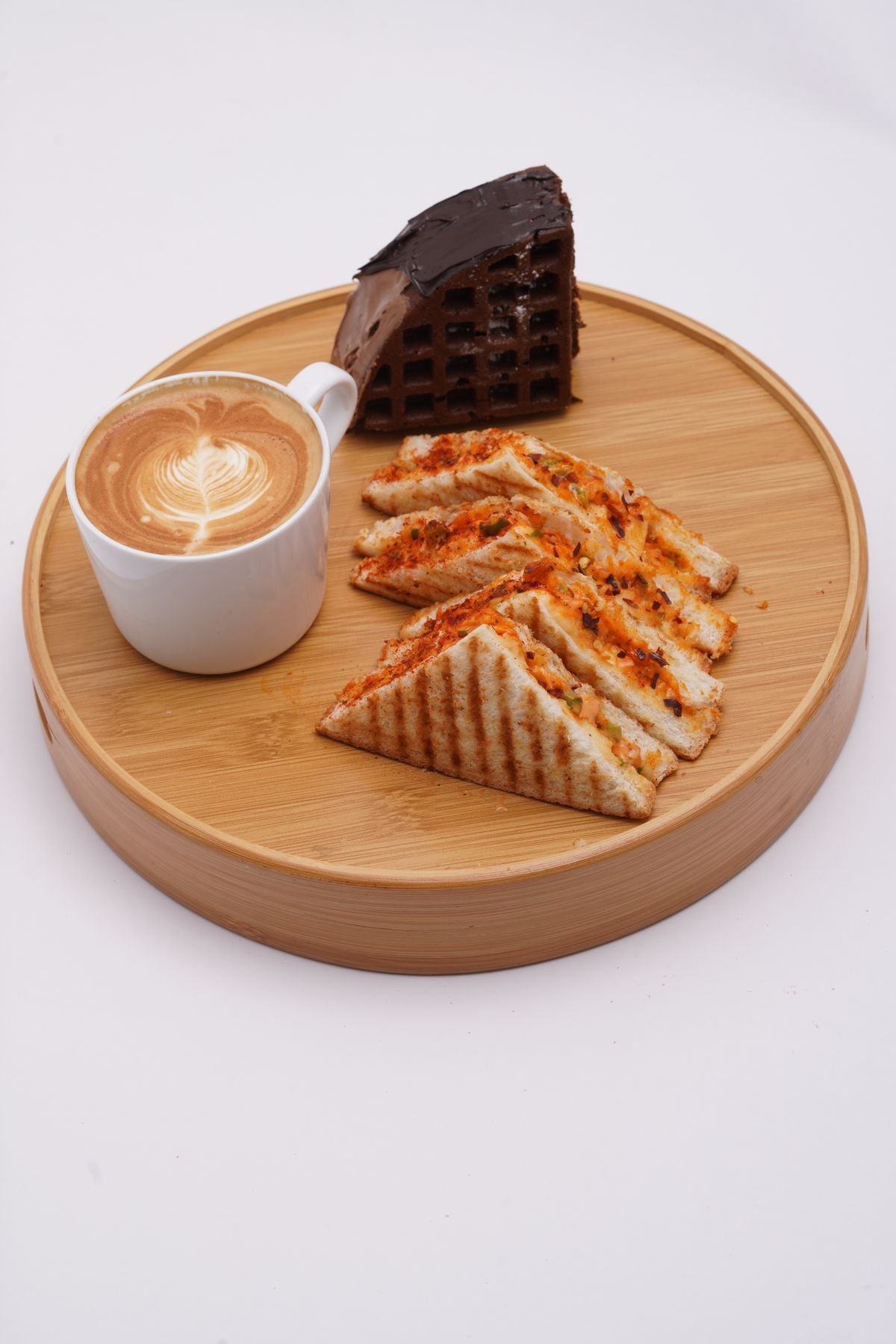 A coffee, a sandwich and a slice of chocolate cake on a wooden platter, used as an editorial illustration for “Why regional menus reflect local tastes”