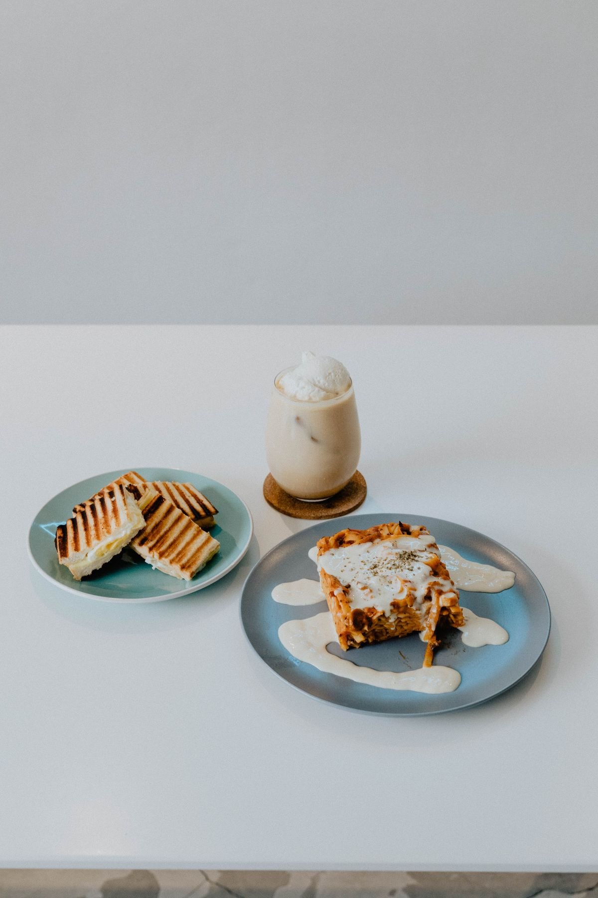 An iced coffee beside pastries on a pale table
