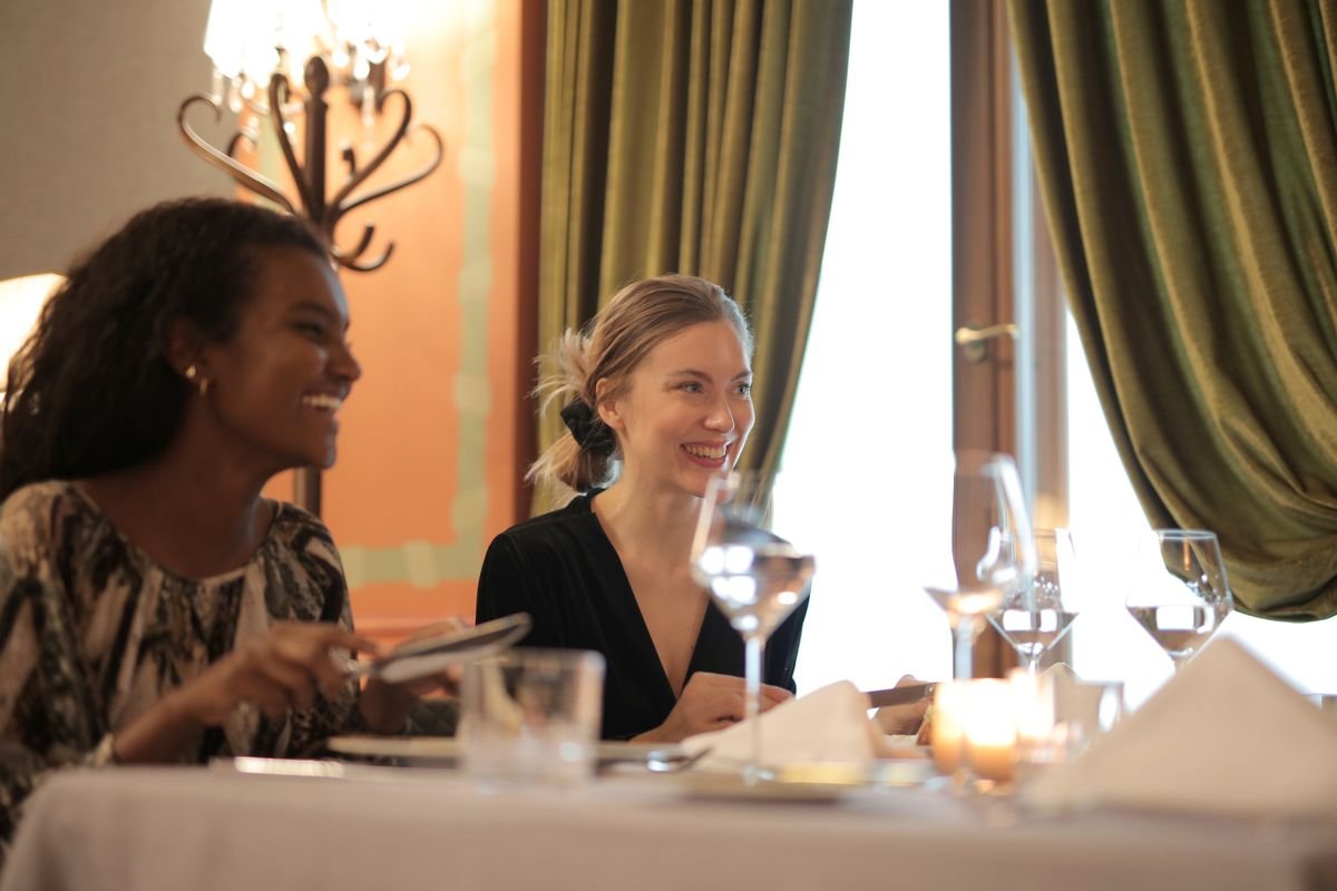 Two friends laughing together over a meal in a restaurant